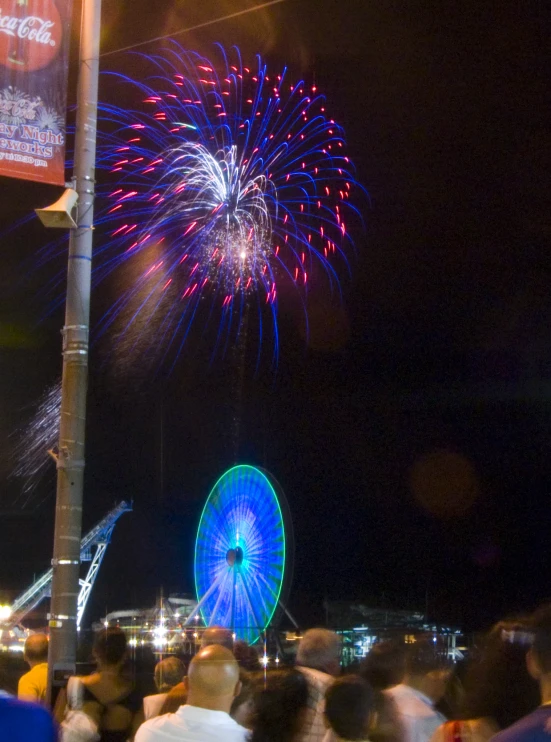 people watching fireworks in the night sky with people standing around