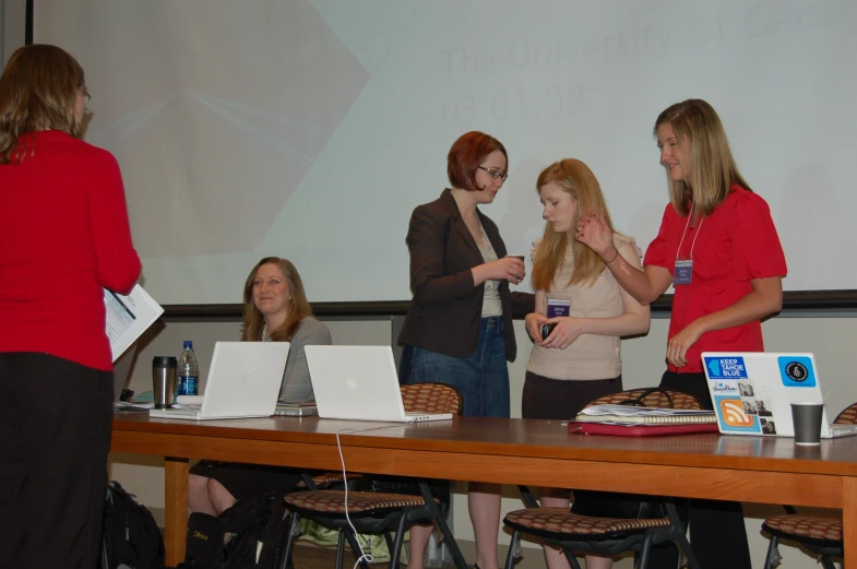 a group of women talking in front of a screen