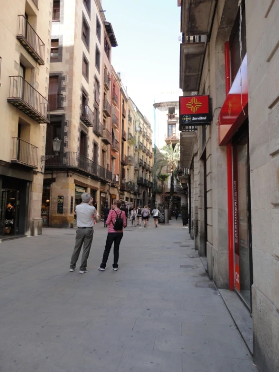 several people are walking down a street with buildings behind them