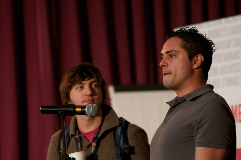 two people are standing behind a microphone