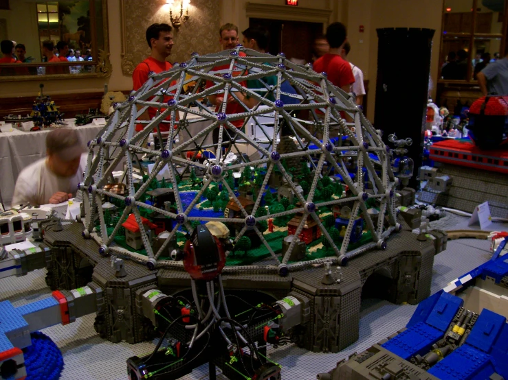 a group of men stand around a model of a spaceship