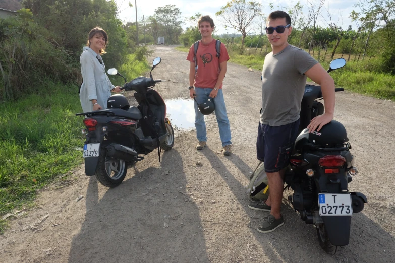 three men pose in the middle of a gravel road