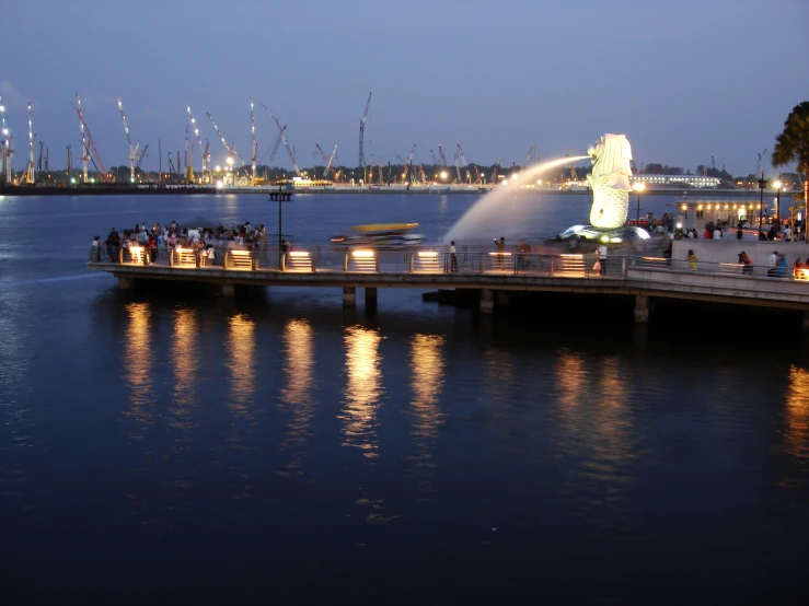 a very large fountain next to a bridge at night