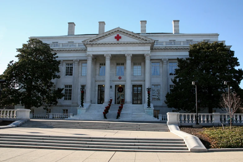 a white building with steps to it, and trees on both sides of the building