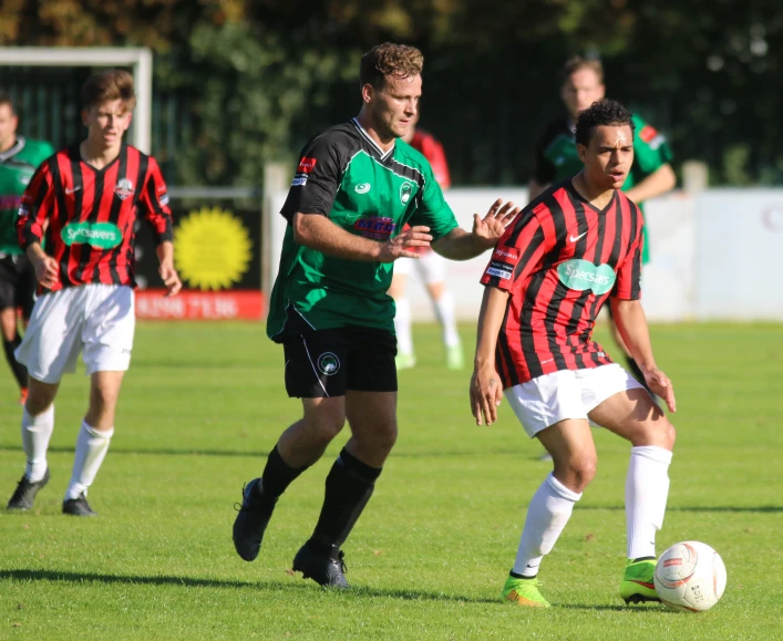 men are playing soccer on the field with other teams in the background