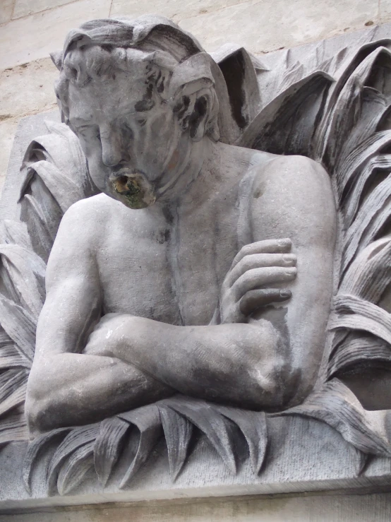 statue sitting with folded arms folded in front of large stone building