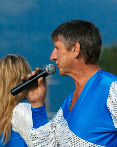 a man singing into a microphone as a woman watches