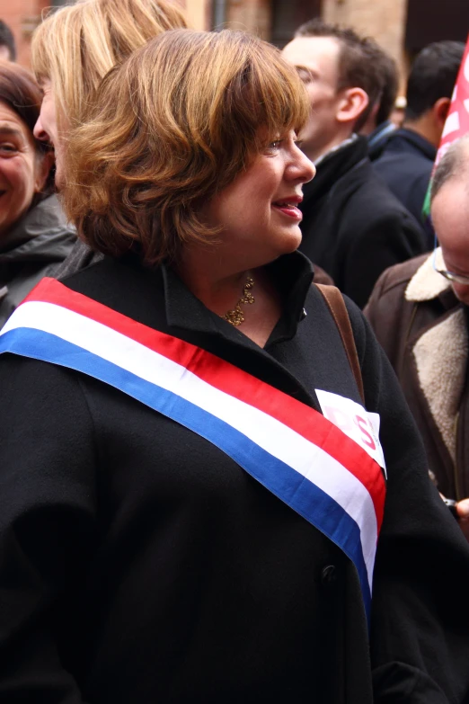 a woman in a crowd with a ribbon on her jacket