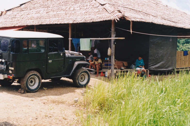 an off road jeep parked in front of a hut