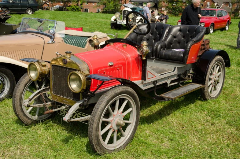 an old fashioned motor bike and car sit parked on the grass