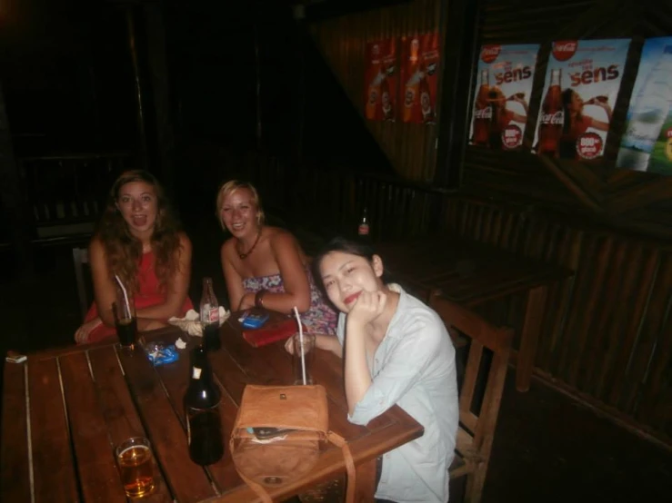 three women sitting at the table, both with a beer
