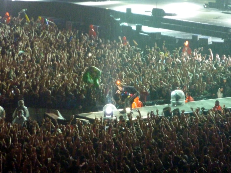 a big crowd is at the stage with their hands raised