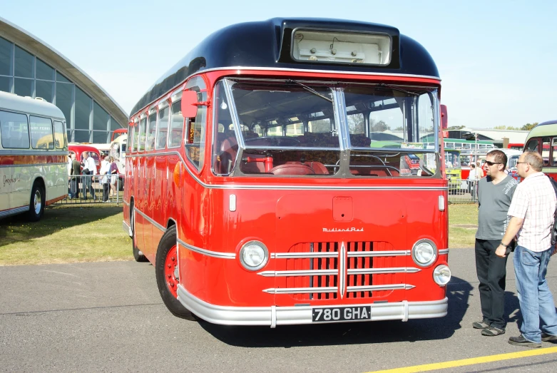 a group of people standing next to an old bus