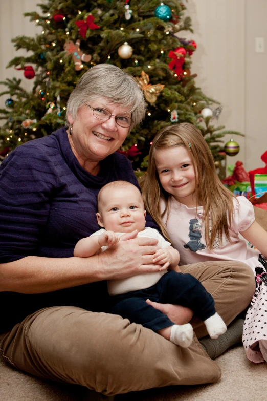 an older lady and two children in front of a christmas tree