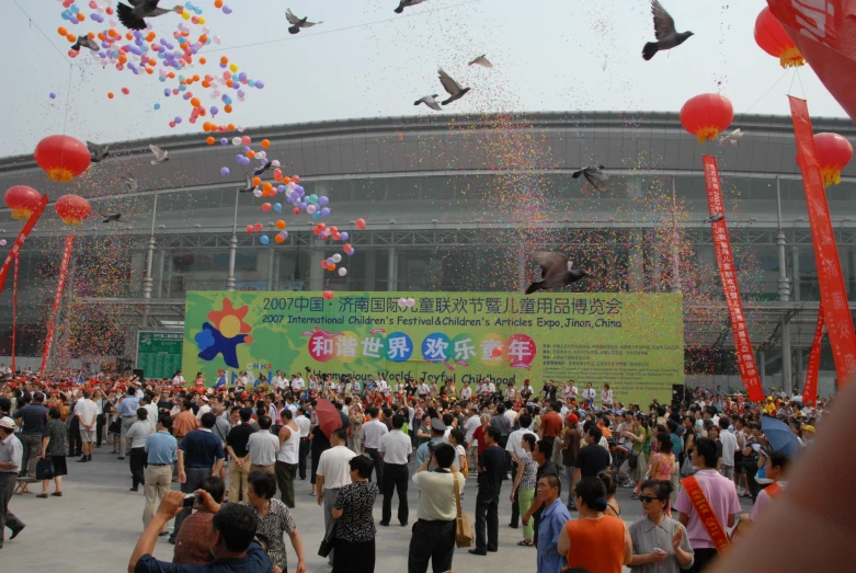 many people in a crowd are watching colorful balloons