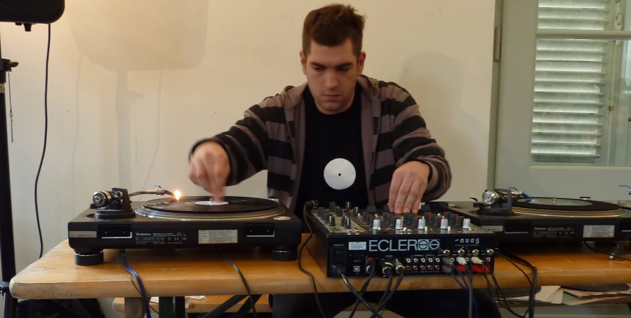 a man plays dj equipment as he works his decks