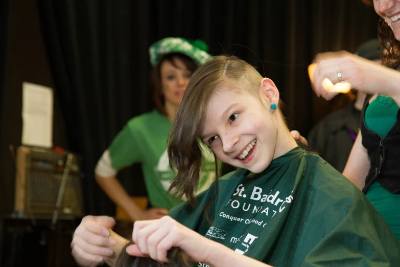 a child gets her hair cut by a woman