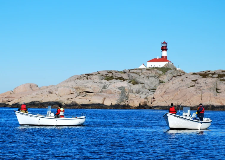 several boats floating in front of a lighthouse in the ocean