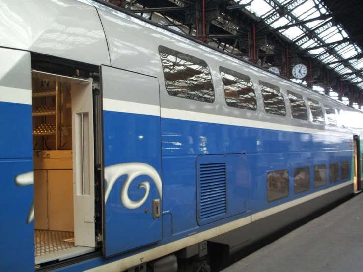 a passenger train sits at the platform with it's doors open