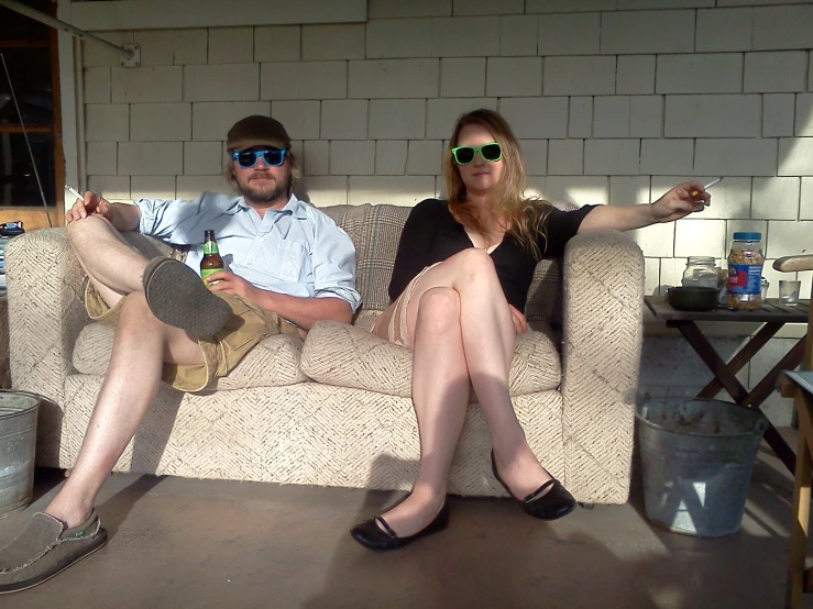 two people sitting on a couch with one in glasses