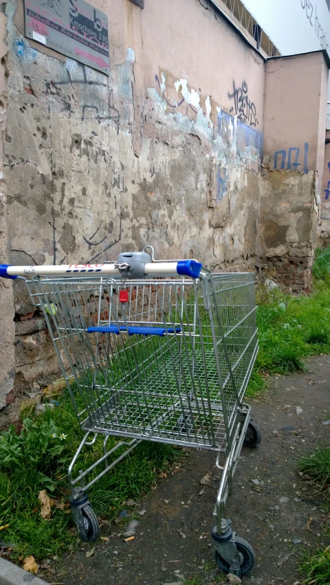 an empty shopping cart is placed in a corner by a broken wall