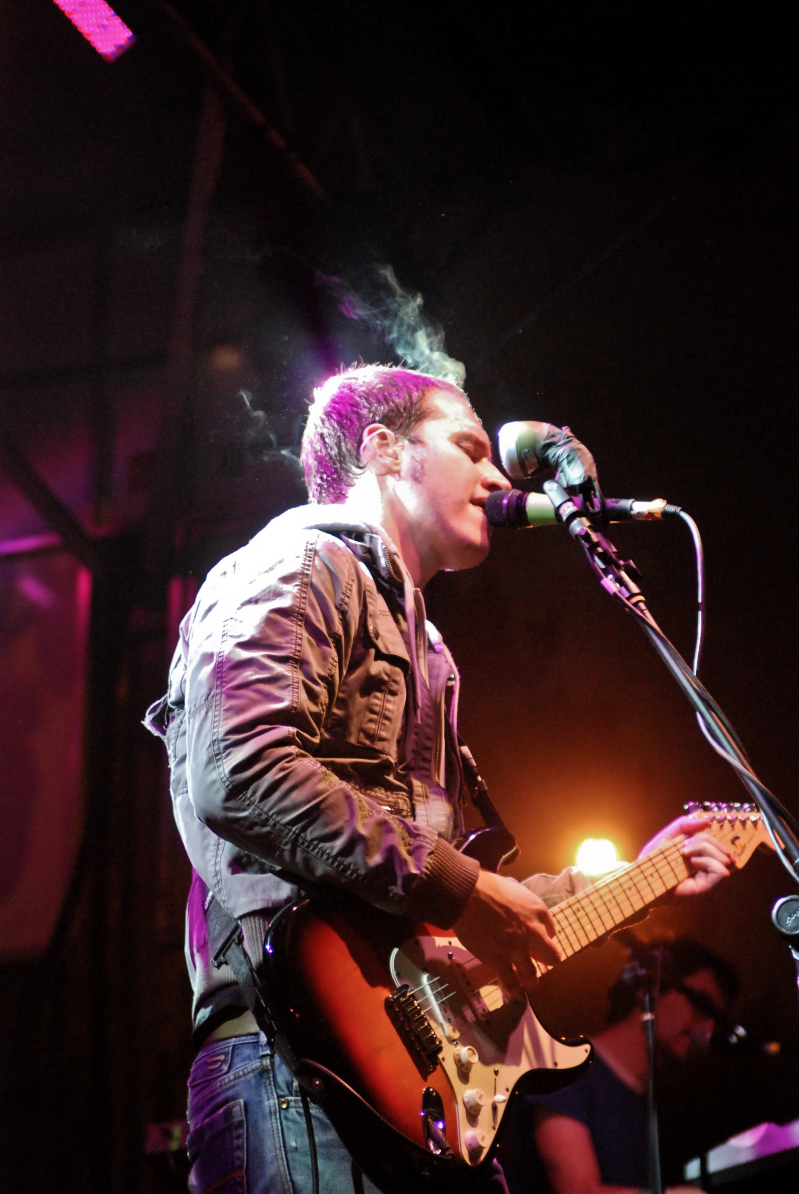 a man playing guitar while singing into a microphone