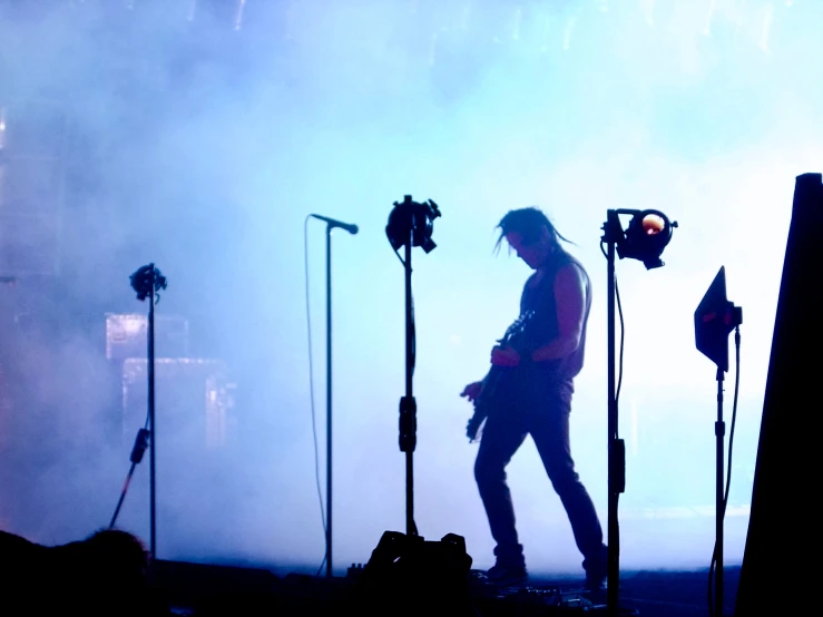 person with microphones walking on stage and lights behind