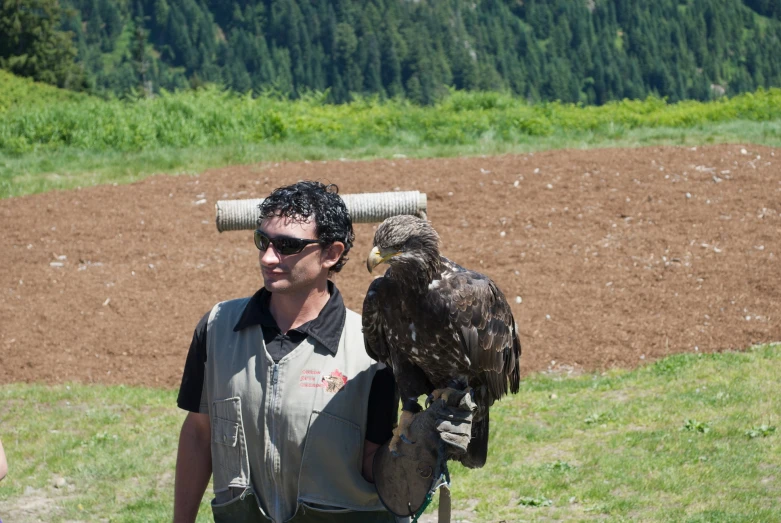 a man in a black and white shirt is holding a bird on his shoulders