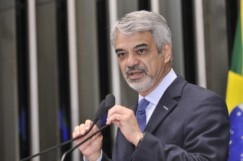 a man in suit and tie holding a microphone