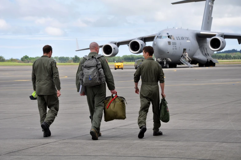 three people wearing air force uniforms walking along a tarmac