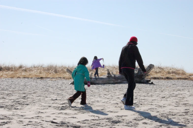 a man walking across a sandy beach holding a child