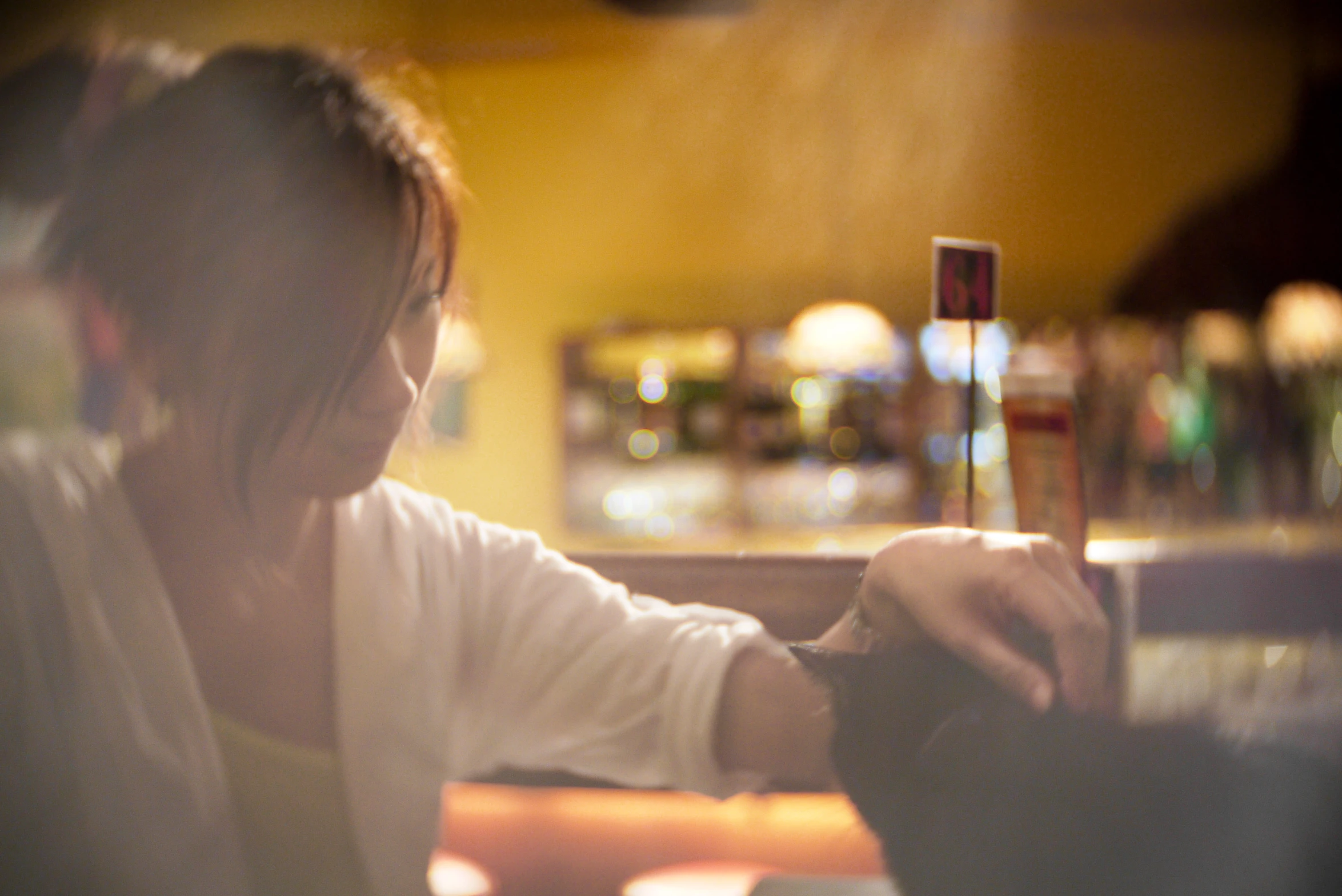 a woman sitting at a bar and holding a cell phone up to a stick