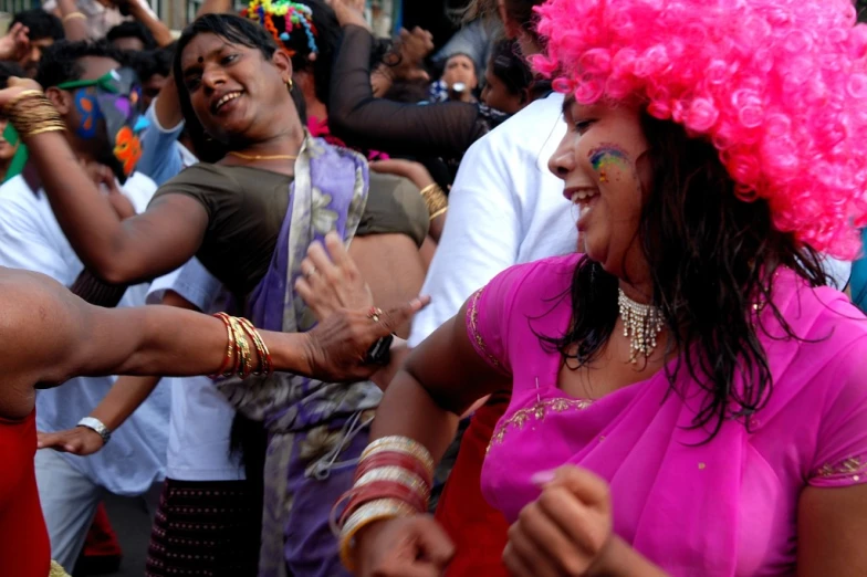 a woman dressed as a woman with a colorful wig is shaking hands with another person in an audience