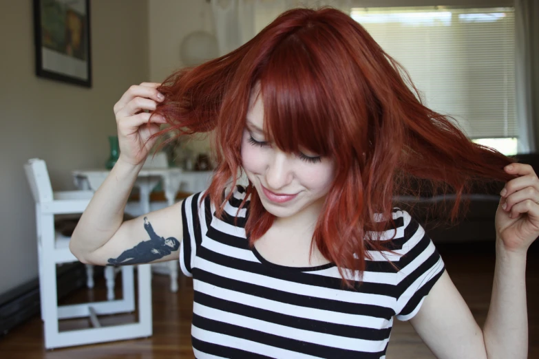 girl with red hair and striped shirt holding back her hair