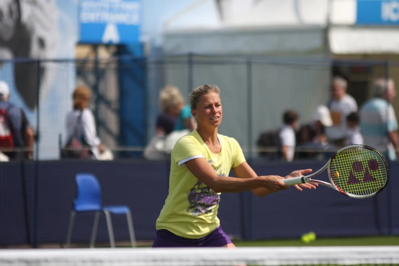 woman in yellow shirt playing tennis in front of fans