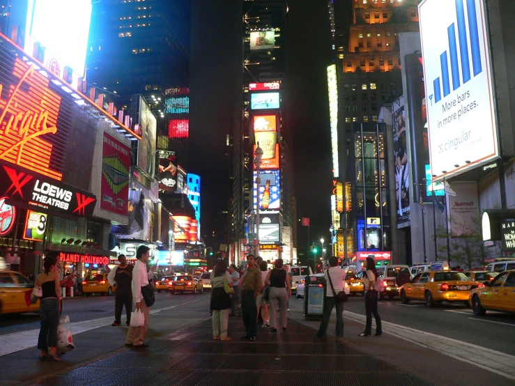 there are many people standing in the middle of a city at night