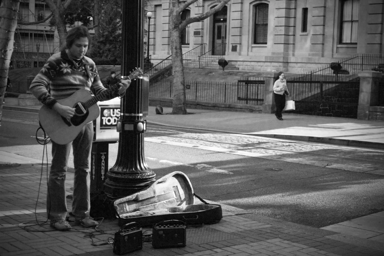 a young man playing the guitar by the light post