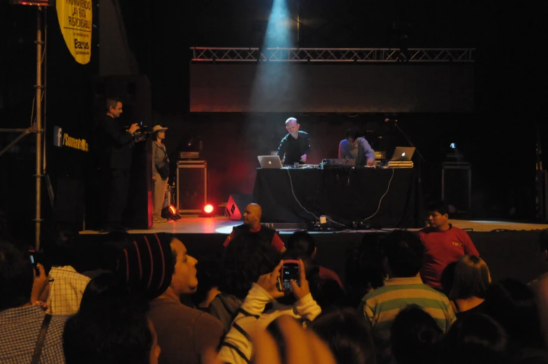 several people watch as a dj performs in front of an audience