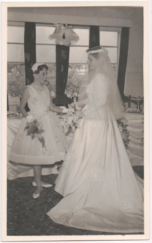 vintage po of two women in bride dresses standing beside each other