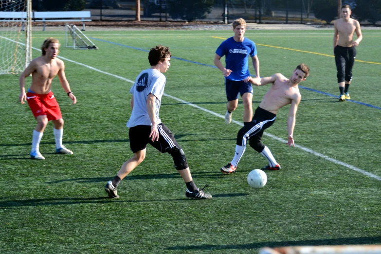 several young men play soccer on a field