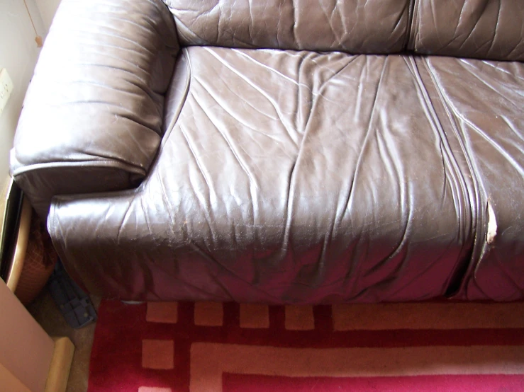 a grey leather couch in a living room next to a pink rug