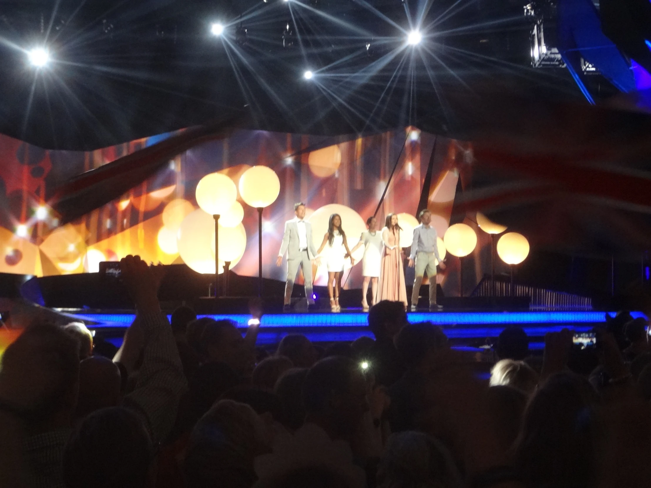 several people stand on a stage lit with spotlights