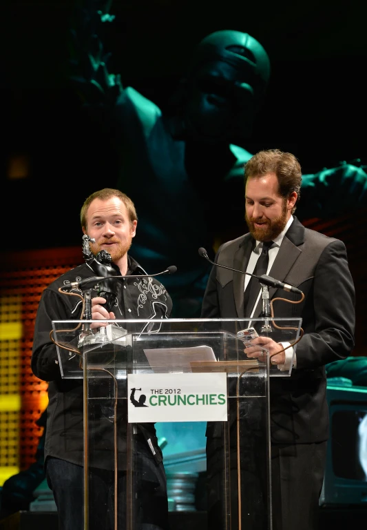 a man standing behind a glass podium talking into a microphone