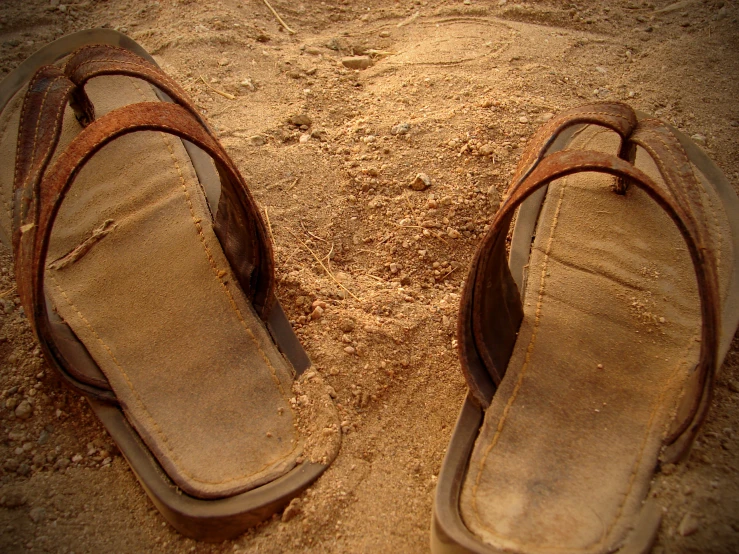 a pair of sandals laying on a sandy surface