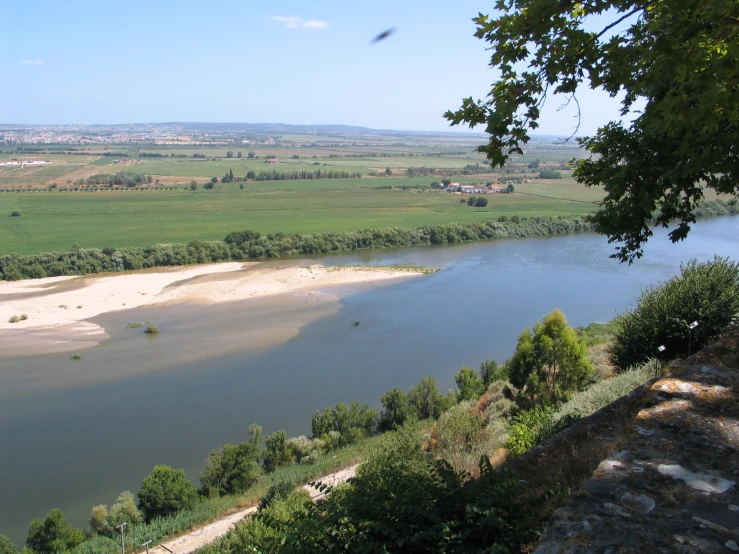 the view of a river that is flowing through some green fields