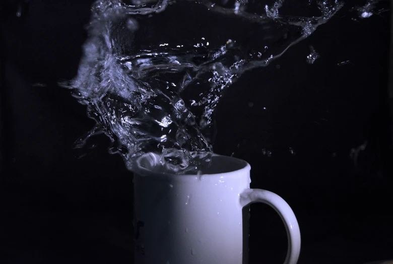 a liquid is splashing into a coffee mug
