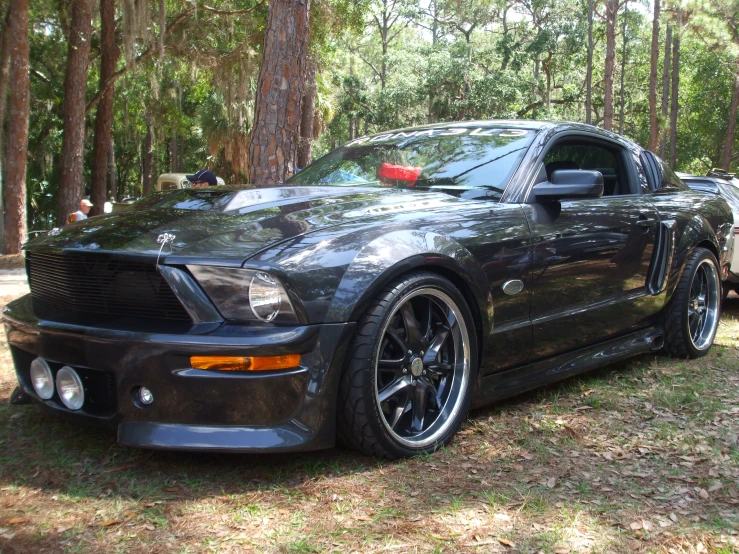 a mustang car with a red tail light is parked in the woods