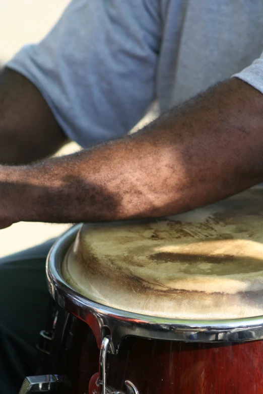 a close up of a man holding onto a wooden drum