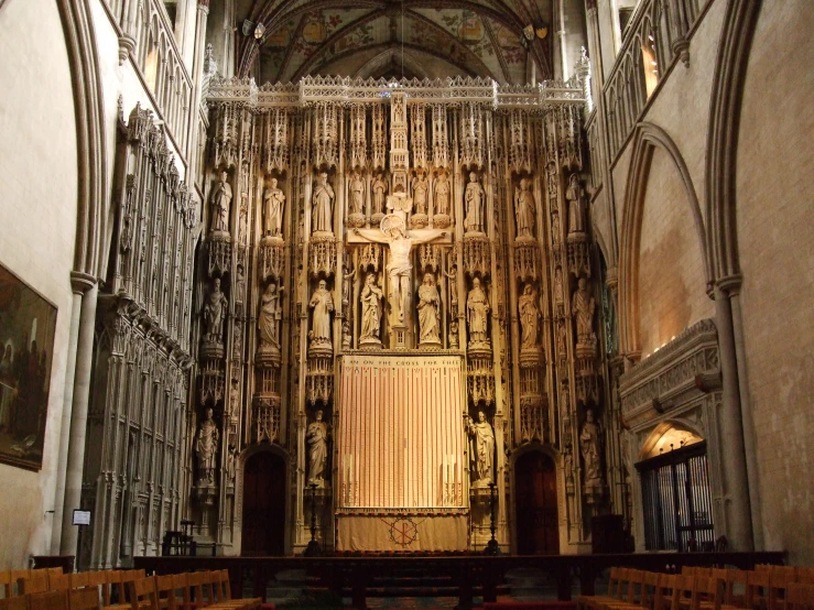 a cathedral with wooden chairs and a giant cross above the doors