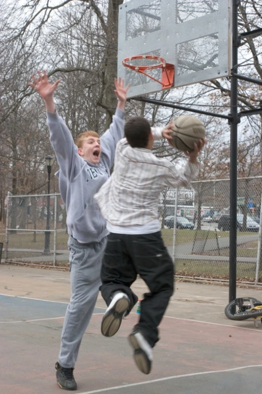 two s playing basketball in a public park